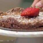 flourless chocolate cake garnished with powdered sugar and resh strawberries