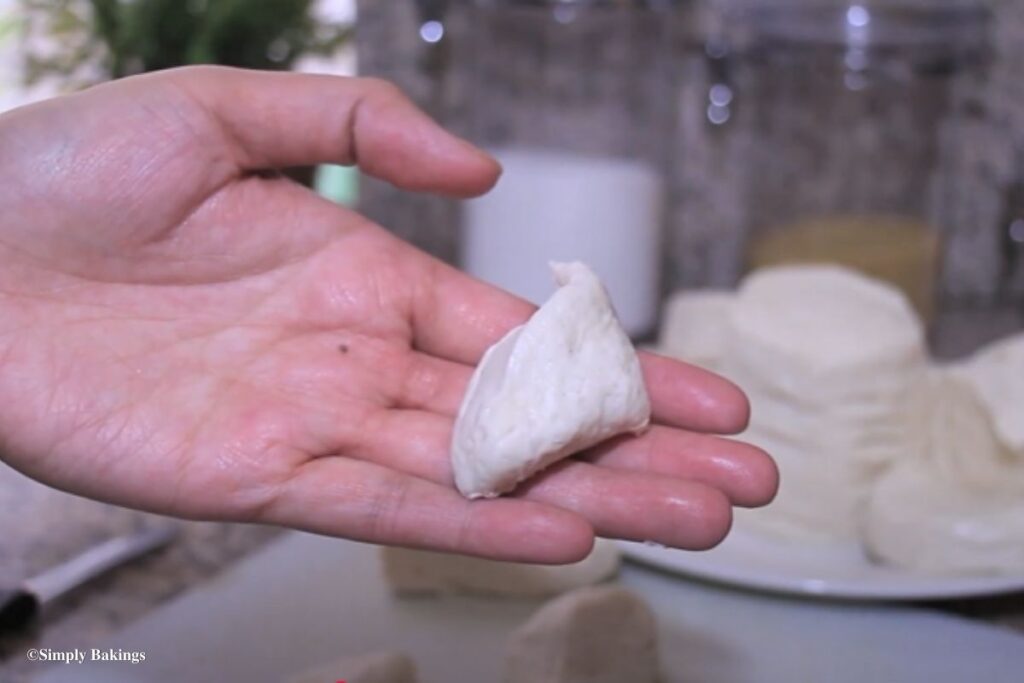 Hand holding up a piece of the bread dough