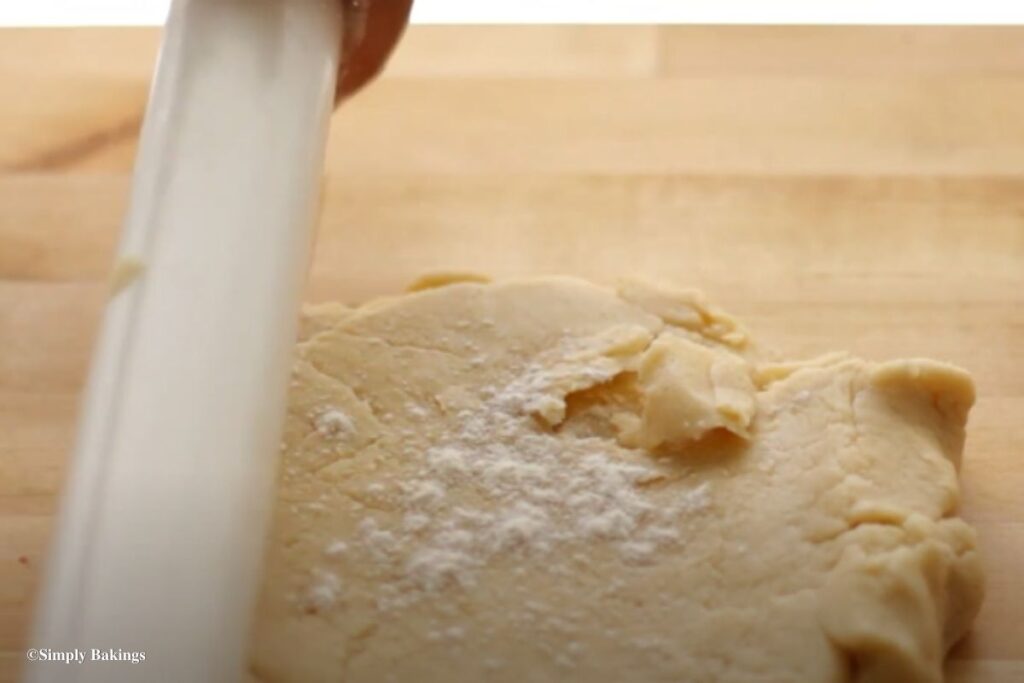 Pie dough being rolled flat on a wooden surface