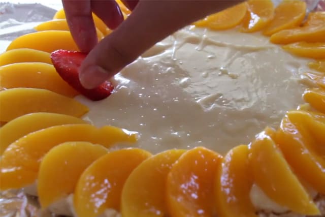 arranging the peace slices and strawberry slices onto the White Chocolate Fruit Tart