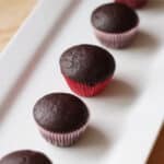 a line of mini chocolate cupcakes on a white rectangular plate