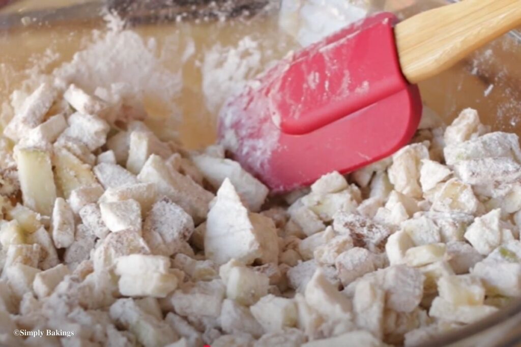 Spatula stirring on a bowl of apple dices
