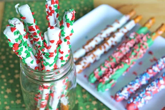 Chocolate pretzel rods decorated with pretty candy sprinkles on a glass and a plate