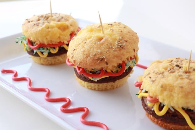hamburger cupcakes with toothpicks on a white plate