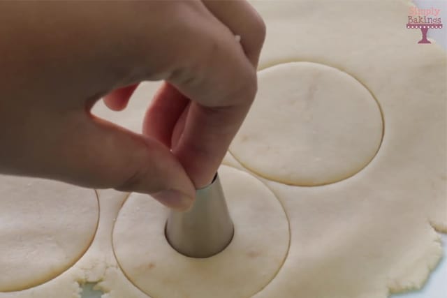 cutting the cookie dough in circles and putting a hole on each cookie