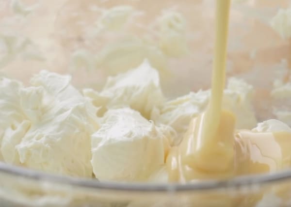pouring condensed milk into cream cheese