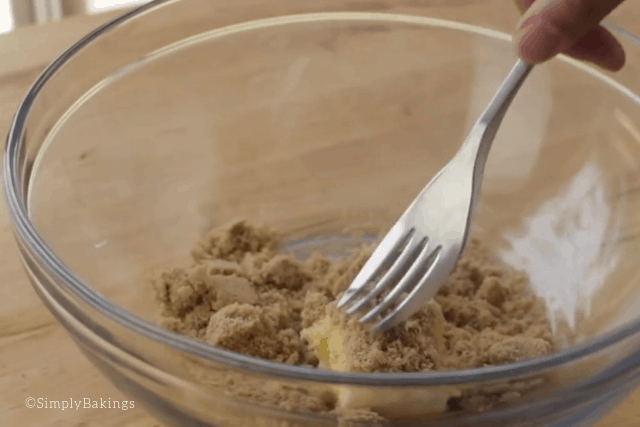 mixing brown sugar and butter on a clear bowl with a fork