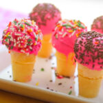 five Ice Cream Cake Pops on a white plate decorated with sprinkles