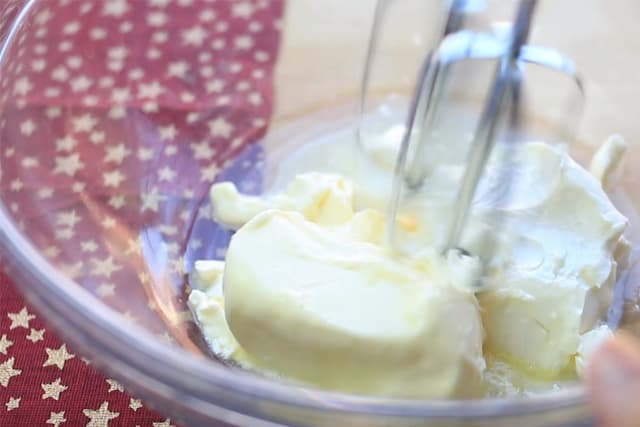 creaming butter with a hand mixer in a clear bowl