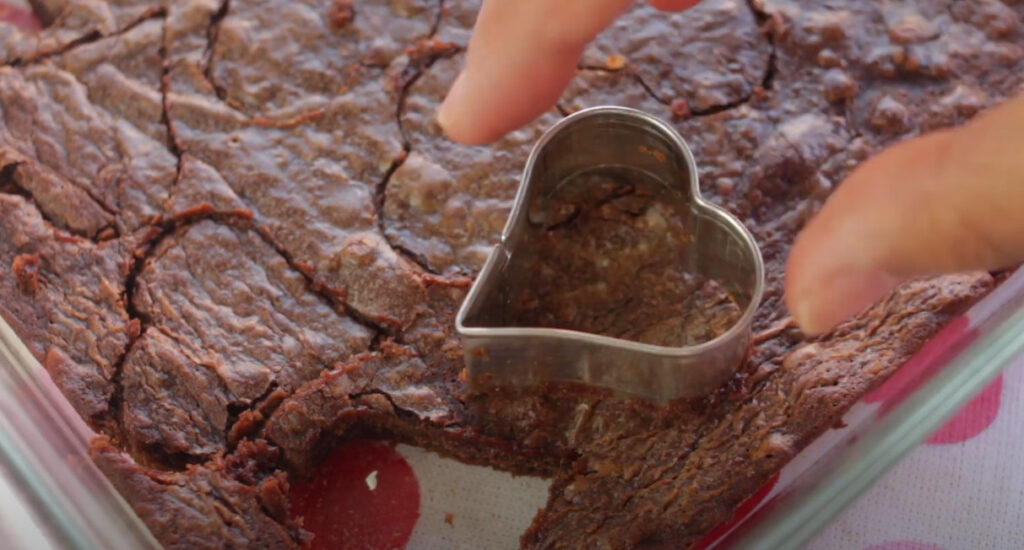 Carving heart-shaped pieces from a freshly baked brownie.