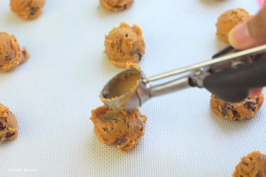 Dough balls being flattened on baking tray