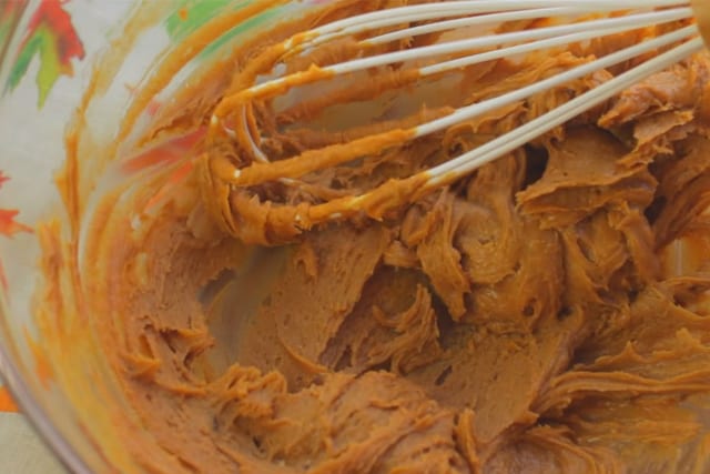 mixing creamy peanut butter together with the egg and sugar using a wire whisk