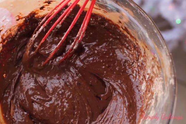 mixed ingredients of the rocky road cookies using a red wire whisk