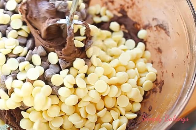 mixing in the dark and white chocolate chips using a handheld mixer