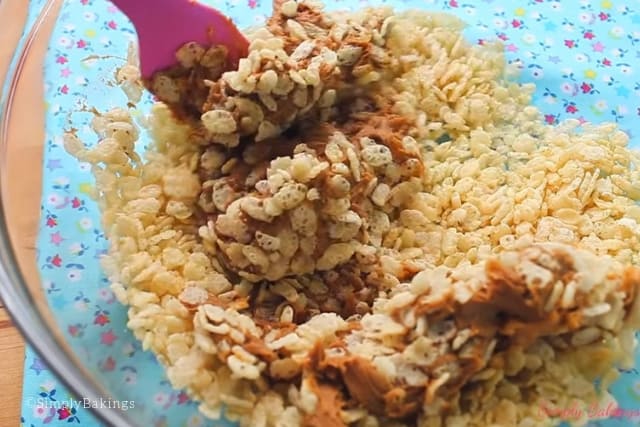 mixing rice krispies and cookie butter in a clear bowl