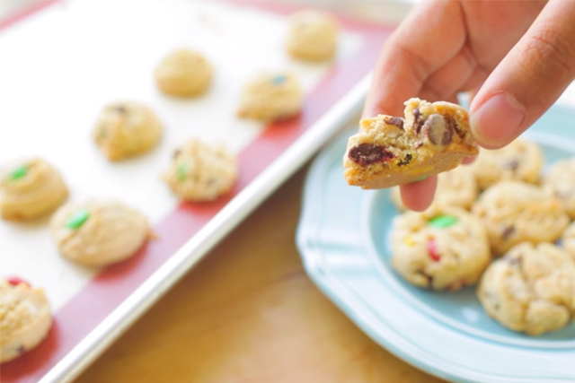 a hand holding a freshly baked assorted candy mix cookies