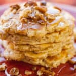 pecan butter pancakes on a red plate garnished with pecans and honey