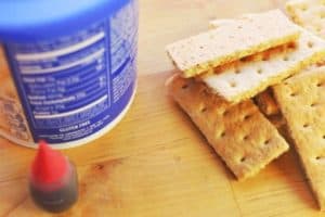 red food color, white frosting, and graham crackers for edible band aid recipe
