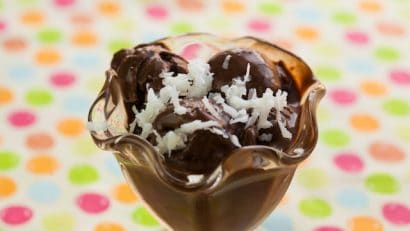scoops of vegan ice cream in a glass cup with dried shredded coconuts topping