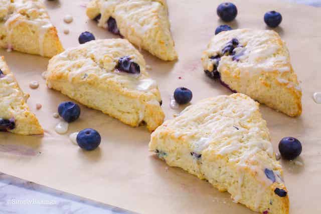 blueberry scones on a parchment paper and garnished with fresh blueberries