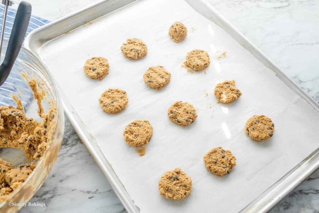 Small pieces of cookie dough flattened on pan