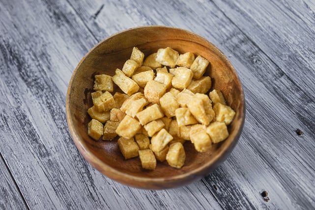 golden brown tofu cubes set aside in a wooden bowl