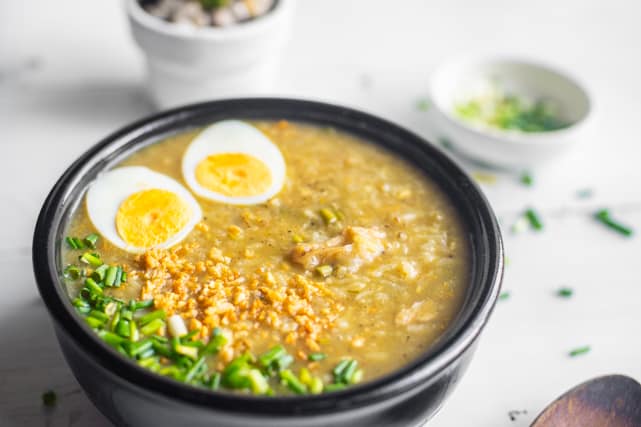 cooked vegetarian congee topped with boiled eggs, taosted garlic bits, and green onions