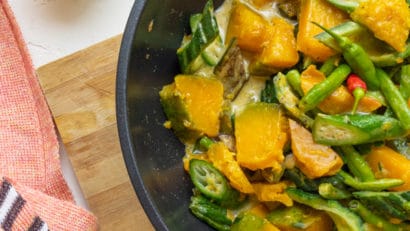 cooked Pinakbet in a pan layed on top of a wooden board