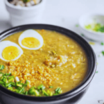 congee topped with boiled eggs, spring onions, and fried garlic bits
