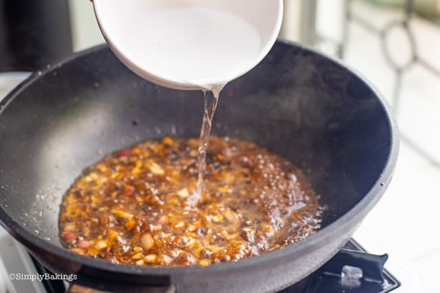 adding water to the vegan humba marinade in the pan