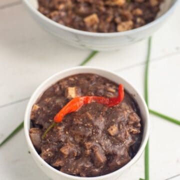vegan dinuguan in two white bowls with a chili peppers on top