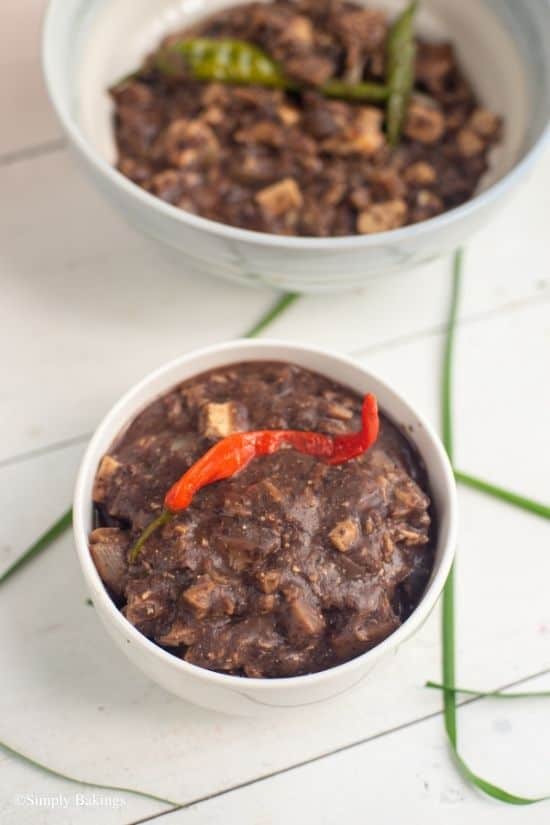 vegan dinuguan in two white bowls with a chili peppers on top
