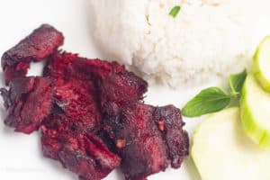 Vegan Tocino on a white plate with rice and cucumber slices