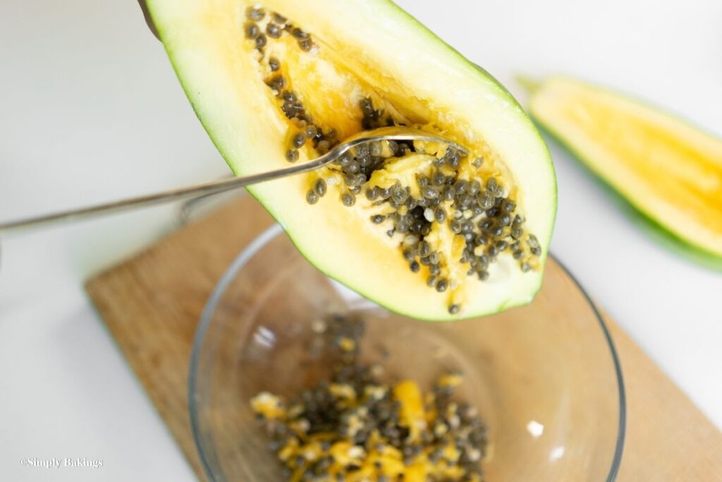 scraping out seeds of papaya using a spoon