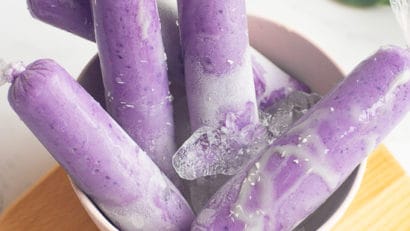 5 ube ice candies in a bowl on top of a wooden board