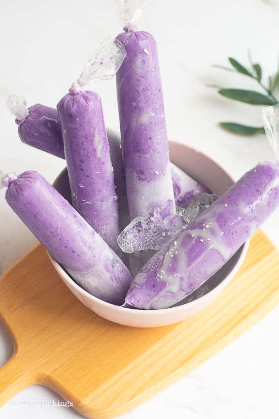 ube ice candy in a bowl on a brown cutting board