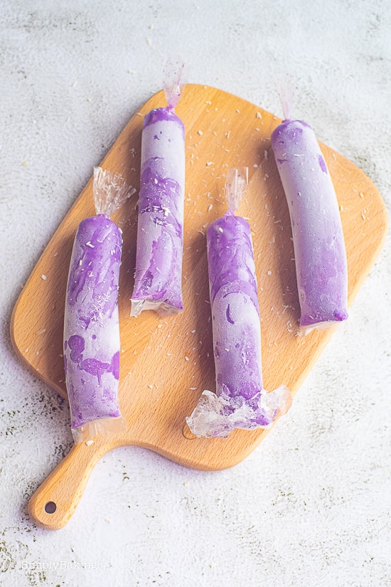 ube ice candy in plastic wrap on a cutting board