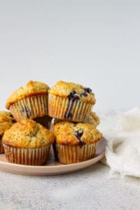 blueberry lemon poppy seed muffins stacked on a pink plate