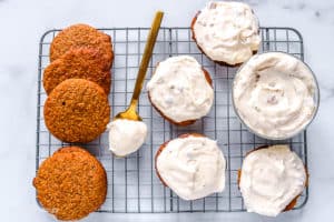 pumpkin whoopie pies on a cookie sheet with pecan cream cheese frosting