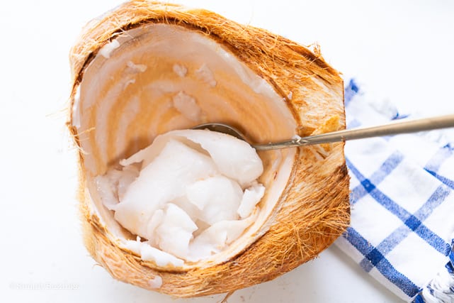 young coconut in a coconut scrapped with a spoon