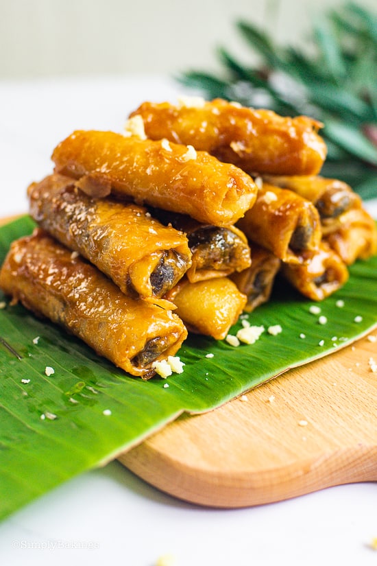 sweet potato spring rolls on a wooden board with a banana leaf in between