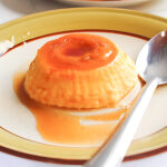creamy leche flan with caramel glaze and a spoon beside it