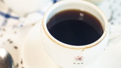a cup of delicious rice coffee with roasted rice beside it