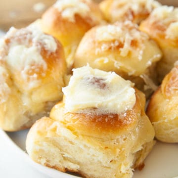 Filipino Ensaymada slathered with butter and cheese on a white plate