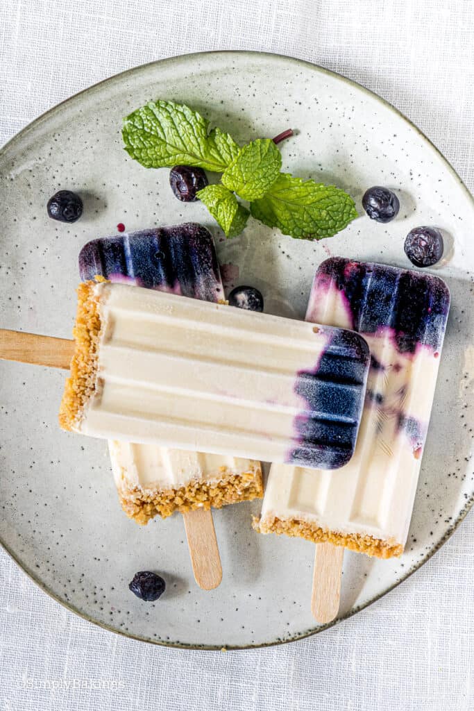 delicious blueberry popsicles on a white plate and garnished with mint leaves and blueberries