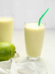 delicious green mango shake in a tall glass with a green straw