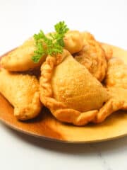 delicious empanadas on a round wooden plate