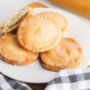 air-fried mini pumpkin pies on a white plate beside a rolling pin beside