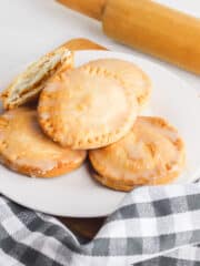 air-fried mini pumpkin pies on a white plate beside a rolling pin beside