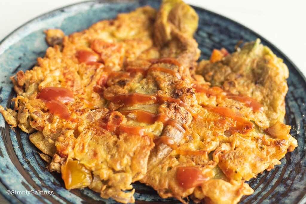 tortang talong on a plate with drizzled with ketchup on top